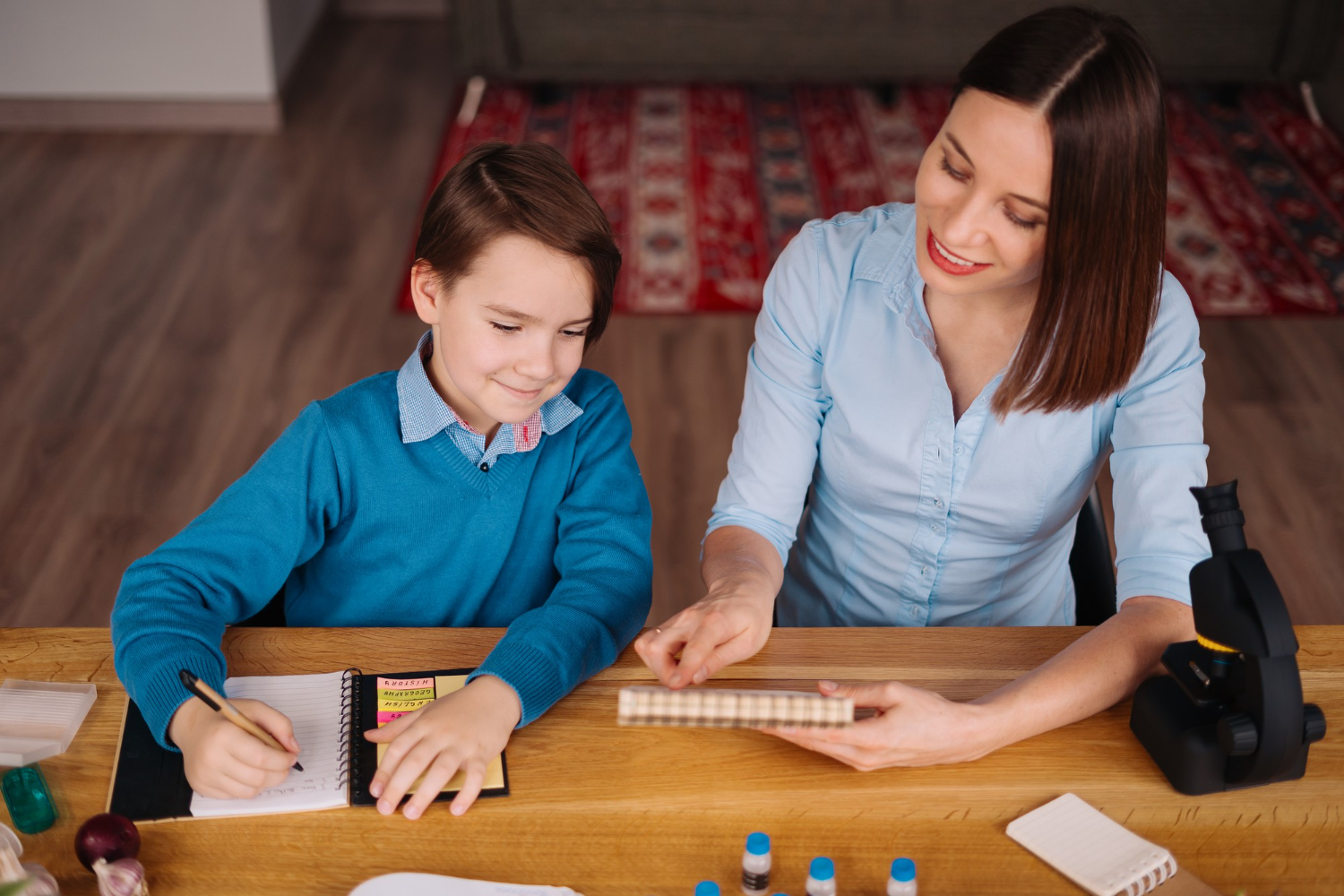 An expert phonics teacher in Dubai smiles while showing a child how to sound out a word using a whiteboard, demonstrating a positive, personalized learning environment.