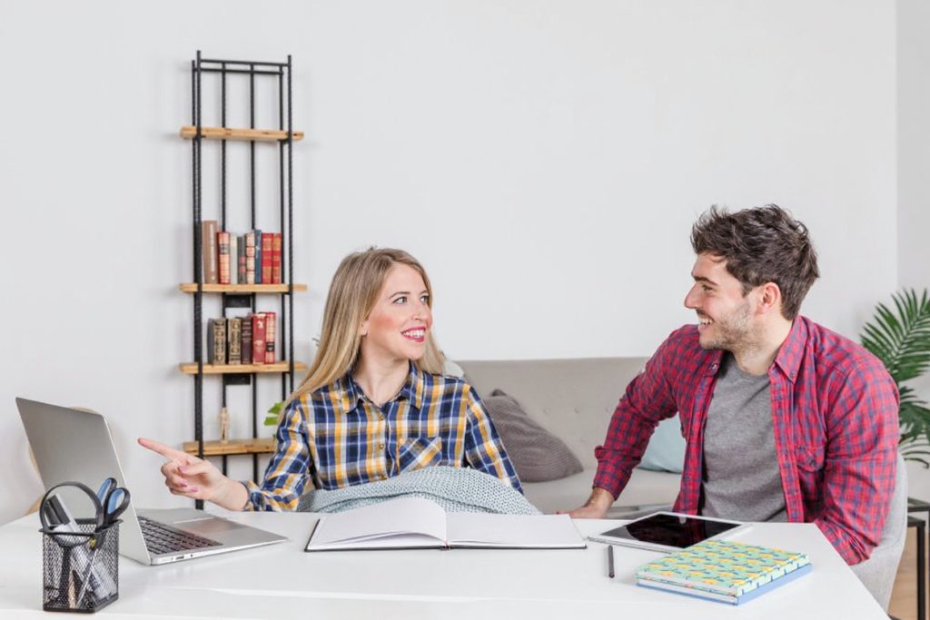 A friendly IGCSE home tutor in Dubai is sitting at a kitchen table with a student, pointing to a diagram in a textbook. The setting is a clean, modern home environment, emphasizing the premium, in-person service.